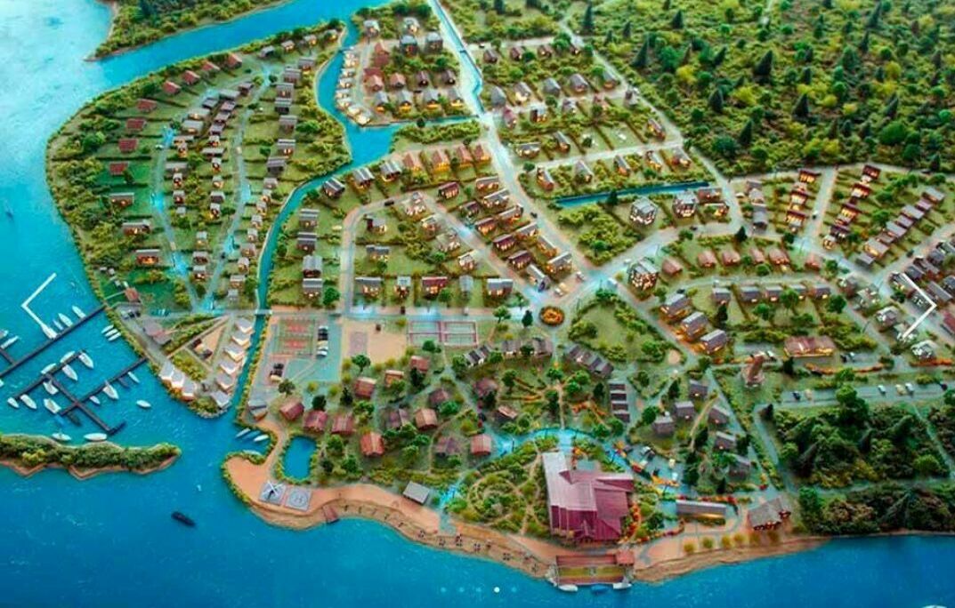 Архитектурный макет коттеджного посёлка на берегу реки с яхт‑мариной Детализированный архитектурный макет загородного коттеджного посёлка у воды: частные дома, дороги, зелёные зоны, пляж и причал для яхт.