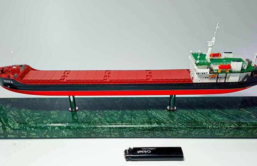 Масштабная модель сухогрузный теплоход (сухогруз) типа "Волга" с грузовыми трюмами На фотографии изображён масштабный макет сухогрузного судна речного или смешанного (река-море) плавания с бортовым именем «Волга». Корпус судна имеет характерную форму с грузовыми трюмами по центру, мостик и надстройка расположены в кормовой части. Судно оборудовано кранами и спасательными средствами, на палубе различимы надстройки, элементы управления, а также спасательные плоты. На палубе установлены люки для доступа к грузовым помещениям. Назначение: Данный тип судна предназначен для перевозки навалочных, генеральных и, возможно, контейнерных грузов по внутренним водным путям и в прибрежных морских районах. Основная задача — транспортировка партий груза между портами, где отсутствует возможность высокоскоростной обработки или где требуется перевозка значительного объёма продукции за одну ходку. Зачем нужен макет: Макеты судов используются для: • Презентации проекта заказчикам и инвесторам • Визуализации инженерных решений на различных этапах проектирования и строительства • Обучения персонала основам управления и эксплуатации • Декоративных целей — макеты выставляются в офисах судостроительных компаний, на выставках и в музеях Легенда модели помогает понять архитектуру будущего судна, его компоновку, а также производит впечатление на потенциальных клиентов.