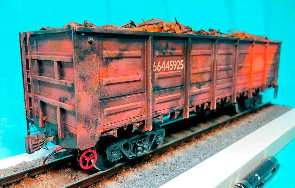Масштабная модель ржавого грузового полувагона на рельсах Реалистичный макет старого грузового полувагона №66445925 с имитацией ржавчины и металлоломом внутри, установленный на модельных рельсах крупным планом