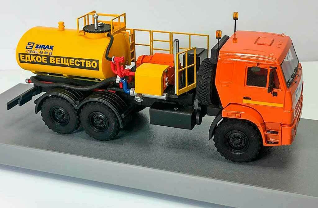 М Модель автоцистерны КамАЗ для едких веществ – макет спецтехники Zirax, изготовленная на заказ для выставки в г. Москва Масштабная модель оранжевого грузовика КамАЗ с жёлтой автоцистерной Zirax и надписью «Едкое вещество», макет спецтехники на подставке, вид сбоку