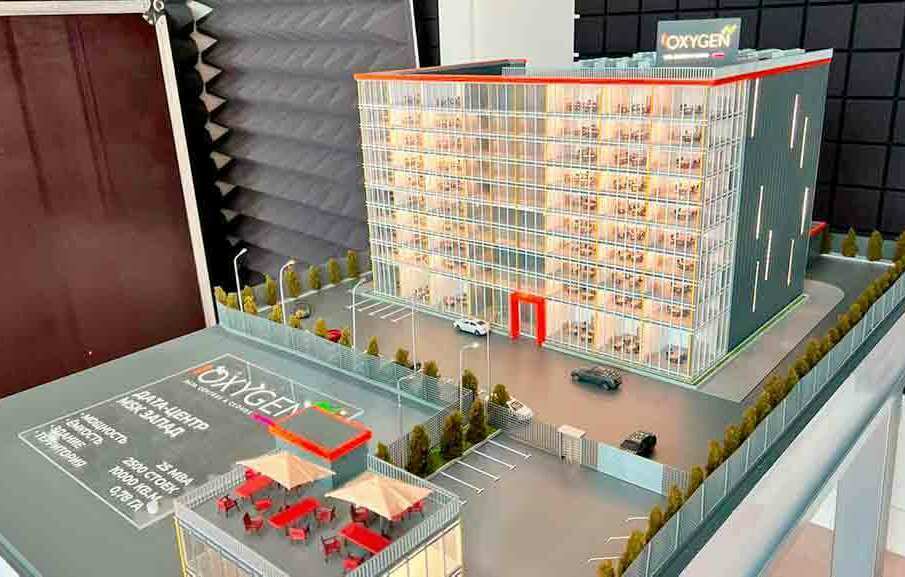 Архитектурный макет бизнес центра Архитектурный макет многоэтажного дата‑центра с парковкой, озеленением и террасой перед главным стеклянным фасадом