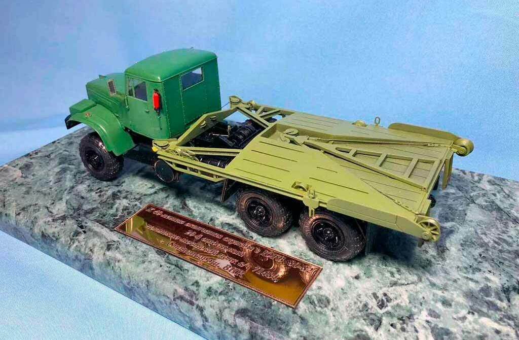 Масштабная модель военного грузовика‑тягача с тралом на подставке изготовленная на заказ для выставки в г. Москва Детализированная масштабная модель зелёного военного грузовика‑тягача с низкорамным тралом, установленной на мраморной подставке для коллекции.