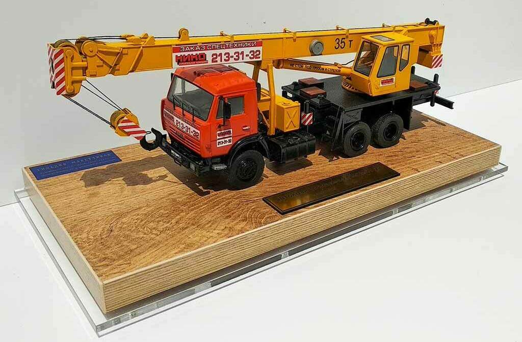 Масштабная модель автокрана КАМАЗ 35 т на деревянной подставке Детализированная масштабной модели автокрана КАМАЗ грузоподъёмностью 35 тонн на деревянной подставке, коллекционная модель строительной спецтехники